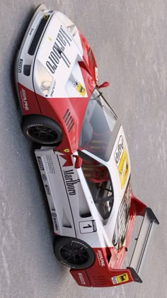 a red and white race car is parked on the pavement in an aerial view from above