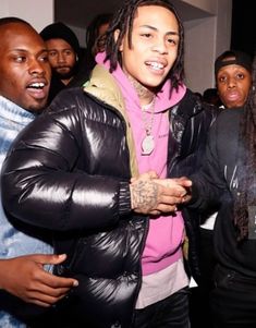 young man with dreadlocks standing in front of other people wearing black jackets and sweaters