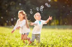 two young children playing with bubbles in the grass