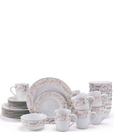 a stack of white dishes and cups with gold designs on the rims are stacked next to each other