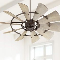 a ceiling fan that is hanging from the ceiling in a room with white walls and windows