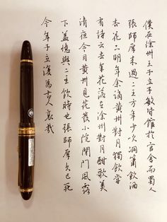 an ink pen sitting on top of a piece of paper with writing in chinese characters