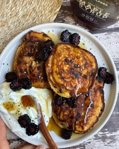 two pancakes on a plate with blueberries and yogurt are being held by a person's hand