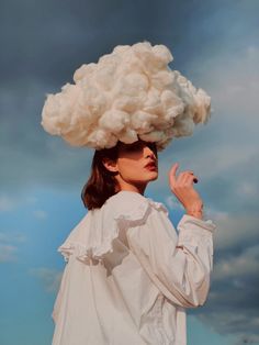 a woman with a cloud on her head standing in front of a cloudy blue sky