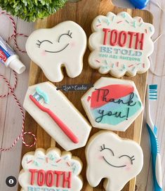 decorated cookies with toothpaste and dental symbols on a cutting board next to flowers