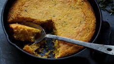 a cake in a pan with a piece missing from it and a spoon resting on top