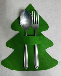 a fork and spoon sitting on top of a green christmas tree shaped placemats