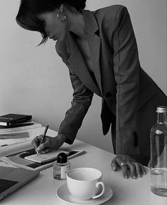 a woman in business attire writing on a desk