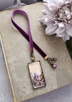 a book with a purple lanyard on top of it and a flower in the background