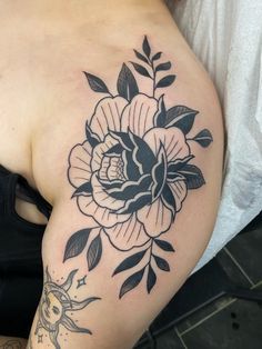 a black and white flower tattoo on the back of a woman's left arm