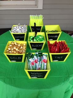 a table topped with lots of candy and candies next to a green table cloth