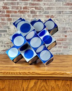 a stack of blue and white plates sitting on top of a wooden table next to a brick wall