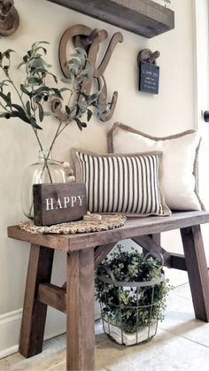 a wooden bench topped with pillows and a vase filled with flowers next to a sign that says happy