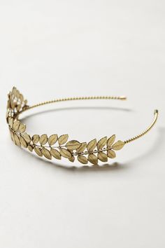 a gold headband with leaves on the top and bottom, sitting on a white surface