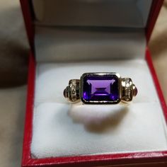 Lovely And Unusual 14kt Yellow Gold Amethyst Ring. High Quality Amethyst Bezel Set Sideways In Between Two Rows Of Channel Set Round Diamonds With A Cabochon Ruby On Either Side. In Excellent Condition, Is About A Size 7 Now, But Sizable. All Stones Are Genuine And 4 Grams In Weight. Luxury Purple Multi-stone Rings, Heirloom 14k Gold Amethyst Ring With Accent Stones, Luxury Purple Multi-stone Sapphire Ring, Elegant Purple Multi-stone Gemstones, Elegant Purple Gemstones With Accents, Purple 14k Gold Jewelry With Accent Stones, Elegant Amethyst Gemstones With Accent Stones, Multi-stone Amethyst Ring In Yellow Gold, Elegant Multi-stone Amethyst Ring In Yellow Gold