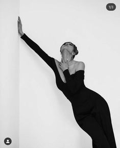 a black and white photo of a woman leaning against a wall