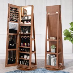 an open wooden jewelry cabinet sitting on top of a blue rug next to a potted plant