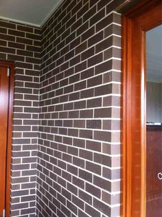 a brick wall in the corner of a room with wooden door and mirror on it