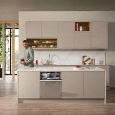 a man standing in a kitchen next to a stove top oven and dishwasher