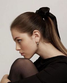 a woman with her hair in a ponytail and wearing black stockings, sitting on the ground