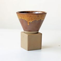 a brown and white vase sitting on top of a block