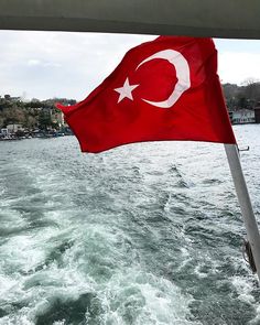 there is a flag on the back of a boat that is in the water with waves