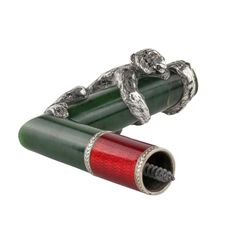 two silver monkey figurines sitting on top of each other next to a red tube