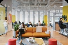 people are sitting at tables and eating in the open air office space with bright yellow walls