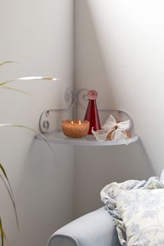 two candles are sitting on a shelf above a bed