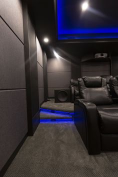 a home theater with black leather seats and blue lighting