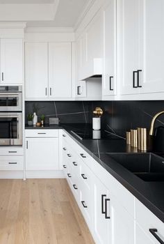 an all white kitchen with black counter tops and gold accents on the oven hoods