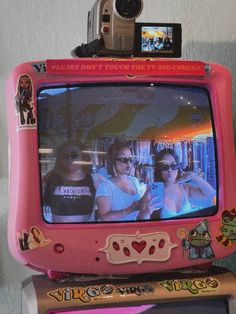 a pink tv with two girls on it and a camera attached to the top one