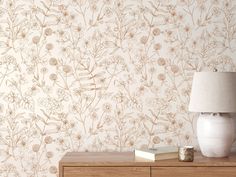 a white vase sitting on top of a wooden table next to a wallpaper covered in flowers