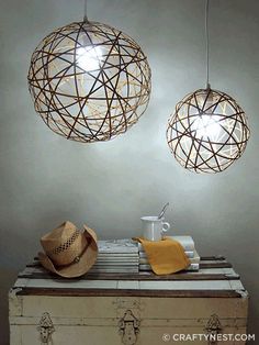 two light fixtures hanging from the ceiling above a trunk with a hat and mug on it