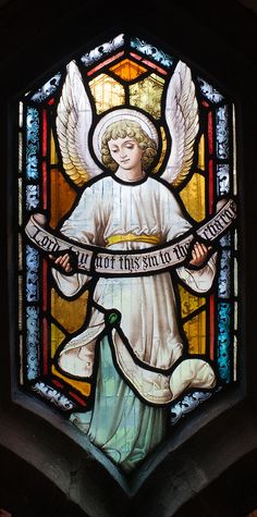 a stained glass window with an angel holding a banner in it's hands and writing on the ribbon