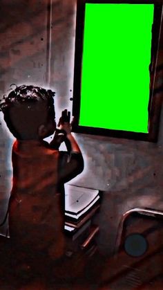 a little boy is looking at a green screen