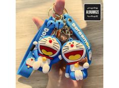 a person holding two key chains in their hand with cartoon characters attached to the keys