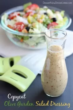 a salad dressing in a glass bottle next to a bowl of salad and cutters