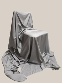 an empty chair covered in a gray cloth on the floor with no one around it