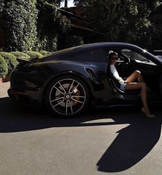 a woman sitting in the driver's seat of a black sports car