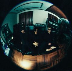 three men sitting on top of a wooden floor