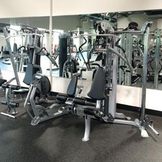 there are many machines in the gym with mirrors on the wall behind them and one is empty