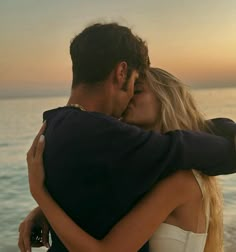 a man and woman embracing each other on the beach