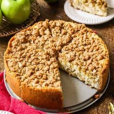 an apple crumb cake on a plate with one slice cut out and the whole pie in the background