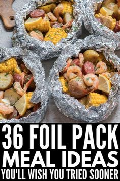 foil packets filled with shrimp, corn on the cob and other foods in them