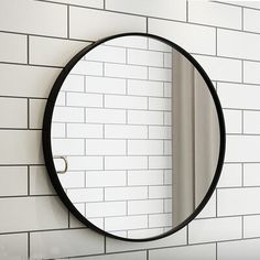 a round mirror mounted to the side of a white brick wall