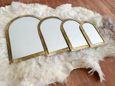 three mirrors sitting on top of a white rug next to a pile of sheepskin