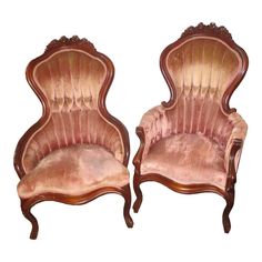 pair of antique chairs with pink velvet upholstered back and arm rests on white background