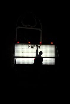 a person standing in front of a sign that says happy