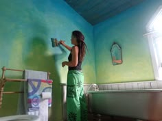 a woman is painting the walls in her bathroom with blue and green paint on the walls